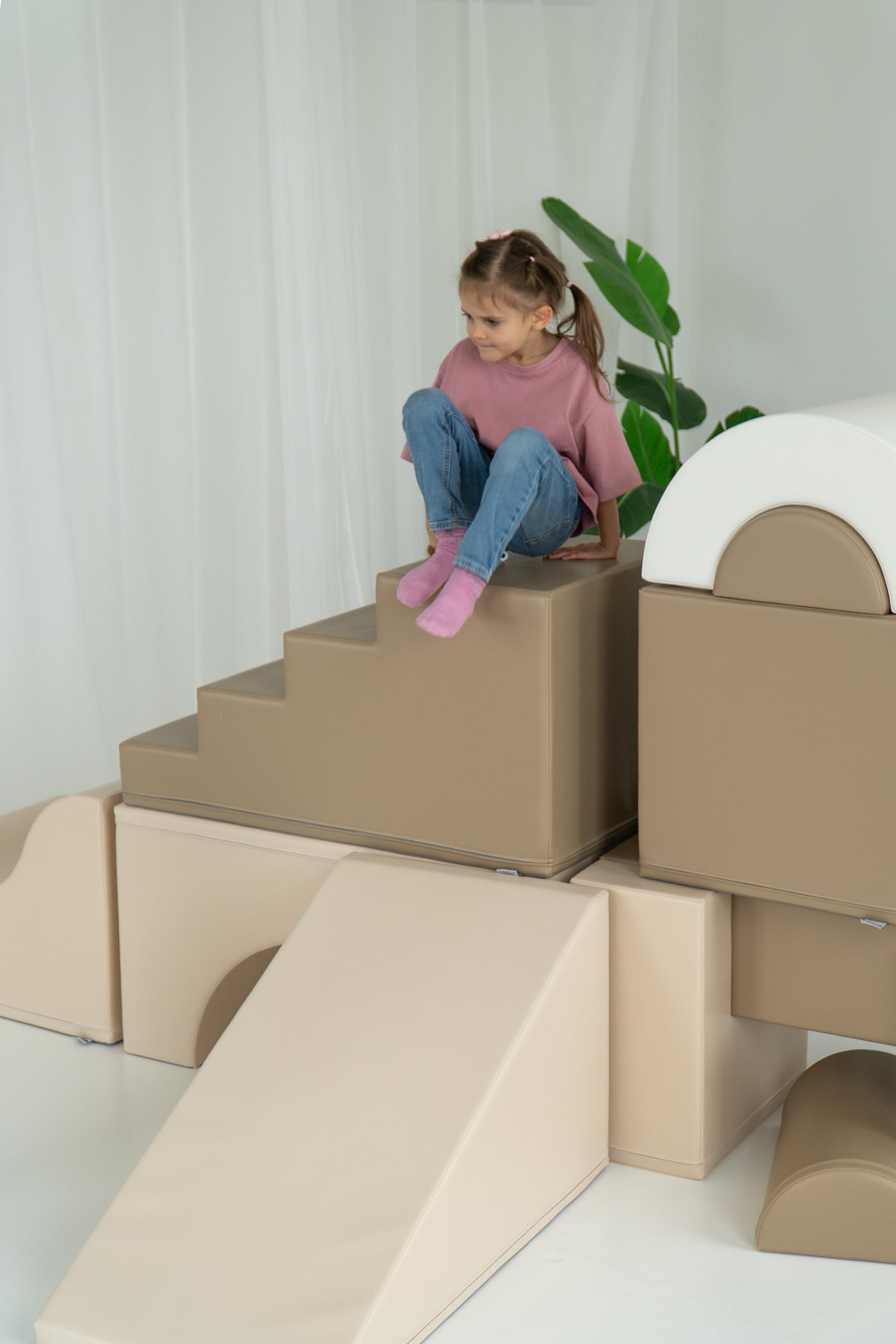 Kind speelt op een beige foamtrap en boog van de IGLU The Gym set